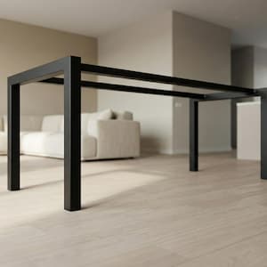 Puede incluir: Una mesa de comedor moderna de metal negro con una tapa rectangular y cuatro patas cuadradas. La mesa está en un espacio de vida minimalista con un sofá y un suelo de color claro. La mesa mide aproximadamente 183 cm de largo, 91 cm de ancho y 76 cm de alto.
