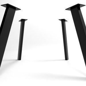 May include: Four black metal table legs with a square base and a slanted design. The legs are arranged in a symmetrical pattern, with two legs on each side.