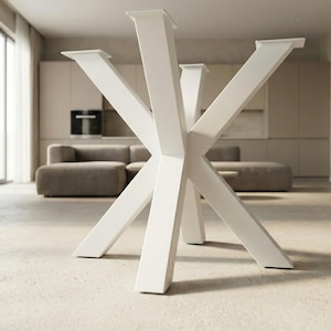May include: White metal table base with a geometric starburst design. The base has eight angled legs that converge in the centre, creating a modern aesthetic. The table base is shown in a neutral-toned room.