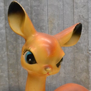 May include: A vintage plastic deer figurine with large, blue eyes and a brown and orange body. The deer has a playful expression and is a great addition to any vintage decor collection.