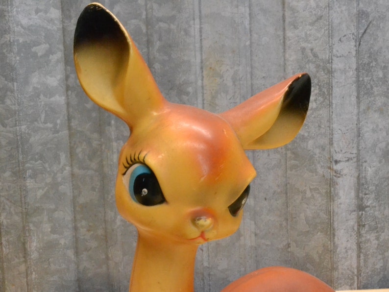May include: A vintage plastic deer figurine with large, blue eyes and a brown and orange body. The deer has a playful expression and is a great addition to any vintage decor collection.
