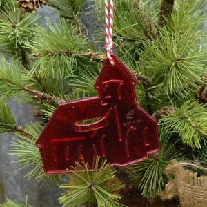May include: Red plastic Christmas ornament shaped like a church with a white and red string attached. The ornament says "Made in USA" on the side.