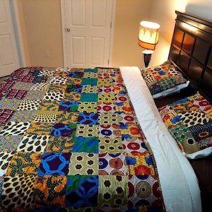 May include: A bed with a colorful patchwork quilt and two matching pillowcases. The quilt is made of various fabrics with geometric and floral patterns in shades of yellow, orange, red, blue, green, and brown.
