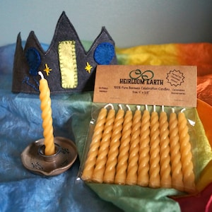 May include: A package of 12 yellow beeswax candles, each twisted into a spiral shape. The candles are packaged in a clear plastic bag with a brown label that reads "Heirloom Earth 100% Pure Beeswax Celebration Candles Size 4" x 3/8".