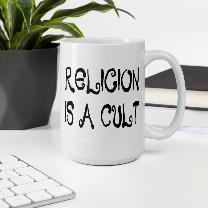 15 ounce white ceramic mug with the phrase Religion is a cult printed on both sides.