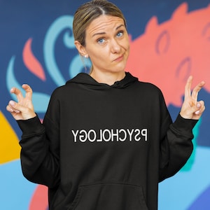 May include: A black hoodie with the word "PSYCHOLOGY" printed in white on the front, worn by a person with blonde hair and a neutral expression.