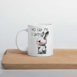 May include: White ceramic mug with a black and white illustration of an angry bunny. The text "NO talk me I angy" is printed on the mug.