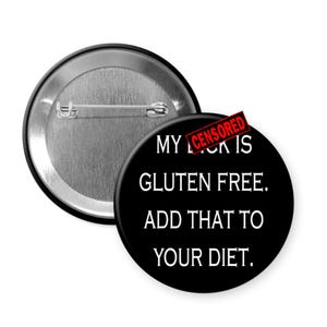 May include: A black button with the text "MY [CENSORED] IS GLUTEN FREE. ADD THAT TO YOUR DIET." The button has a silver pin back and a red "CENSORED" stamp.