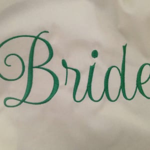 Puede incluir: Tela blanca con la palabra "Bride" bordada en letra cursiva verde.