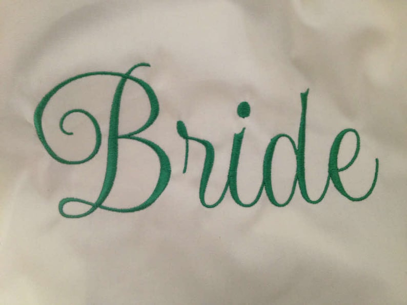 Puede incluir: Tela blanca con la palabra "Bride" bordada en letra cursiva verde.