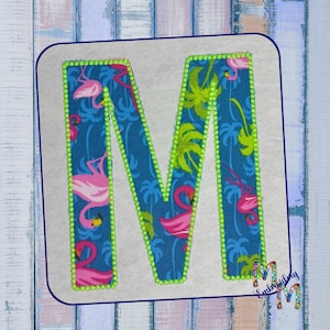 May include: A bright blue and green fabric letter M with a flamingo and palm tree pattern. The letter is outlined in neon green.