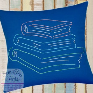 May include: A blue pillow with an embroidered design of a stack of books in different colors. The books are outlined in white, pink, and green thread.
