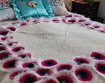 May include: White crocheted throw blanket with a fringe border. The blanket features a repeating pattern of pink, purple, and black circles.