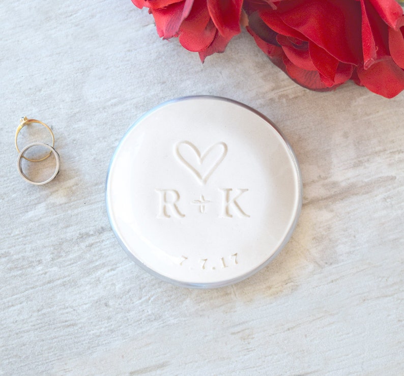 silver rim 3.5 inch glossy white ceramic wedding ring dish engraved with large heart, 2 name initials & date. Minimalist white on white design hand stamped clay pottery personalized wedding gift, wife anniversary present, jewelry trinket holder bowl