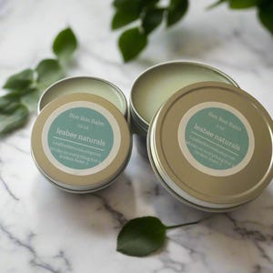 May include: Four small, round, silver-colored tins of "Boo Boo Balm" with light green balm inside. Each tin has a teal label with white text that reads "leabee naturals" and "Works on everything but a broken heart".