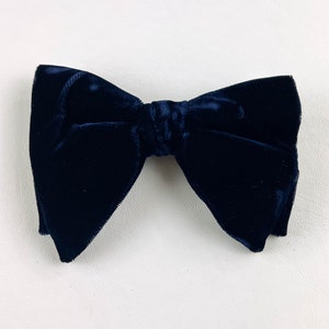 Puede incluir: Una pajarita de terciopelo negro.