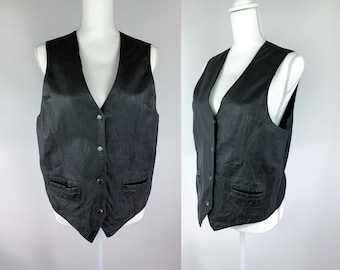 May include: A black leather vest with a V-neck and button closure. The vest has two pockets on the front and a smooth, textured surface.