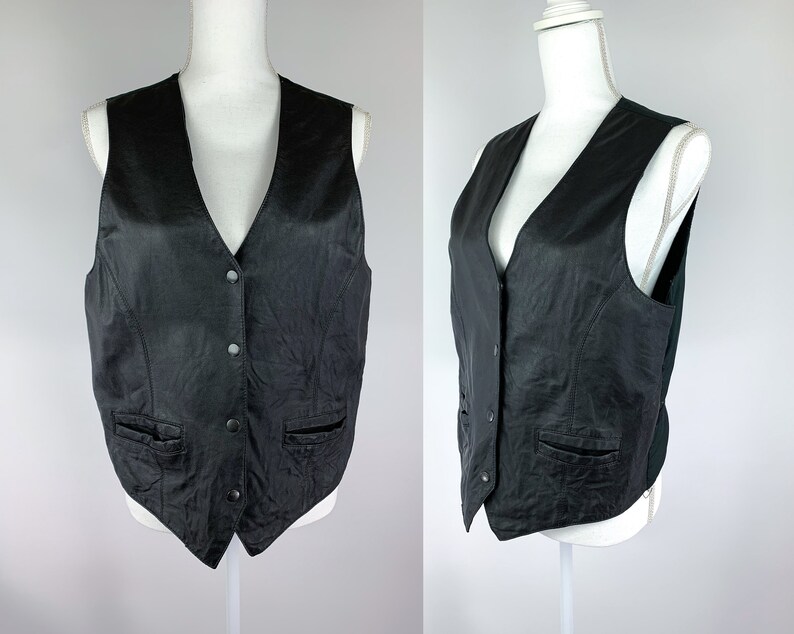 May include: A black leather waistcoat with a V-neck and button fastening. The waistcoat has two pockets on the front and a smooth, textured surface.