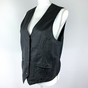 May include: A black leather waistcoat with a V-neck, button fastening, and two pockets.