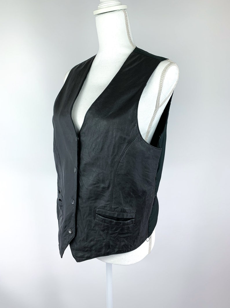 May include: A black leather waistcoat with a V-neck, button fastening, and two pockets.