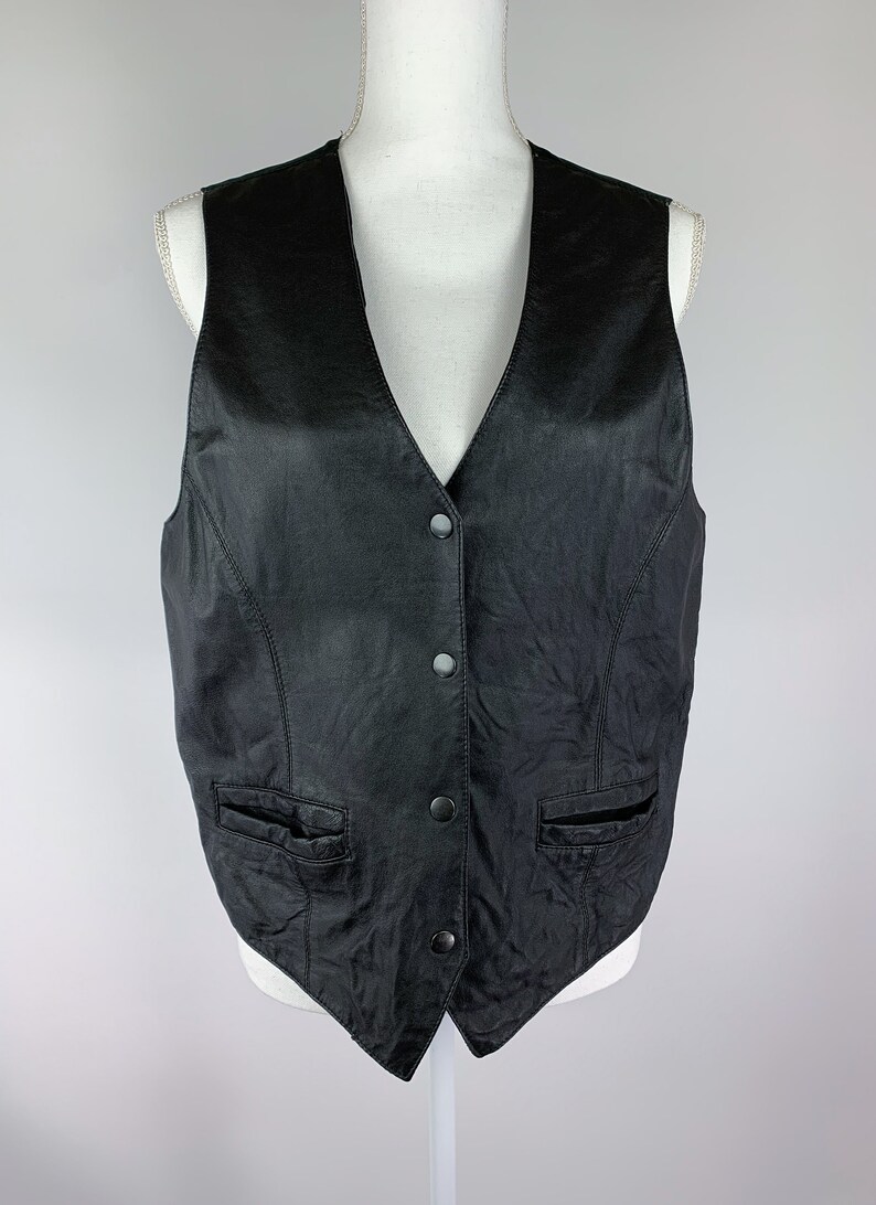 May include: A black leather waistcoat with a V-neck and button fastening. The waistcoat has two pockets on the front.