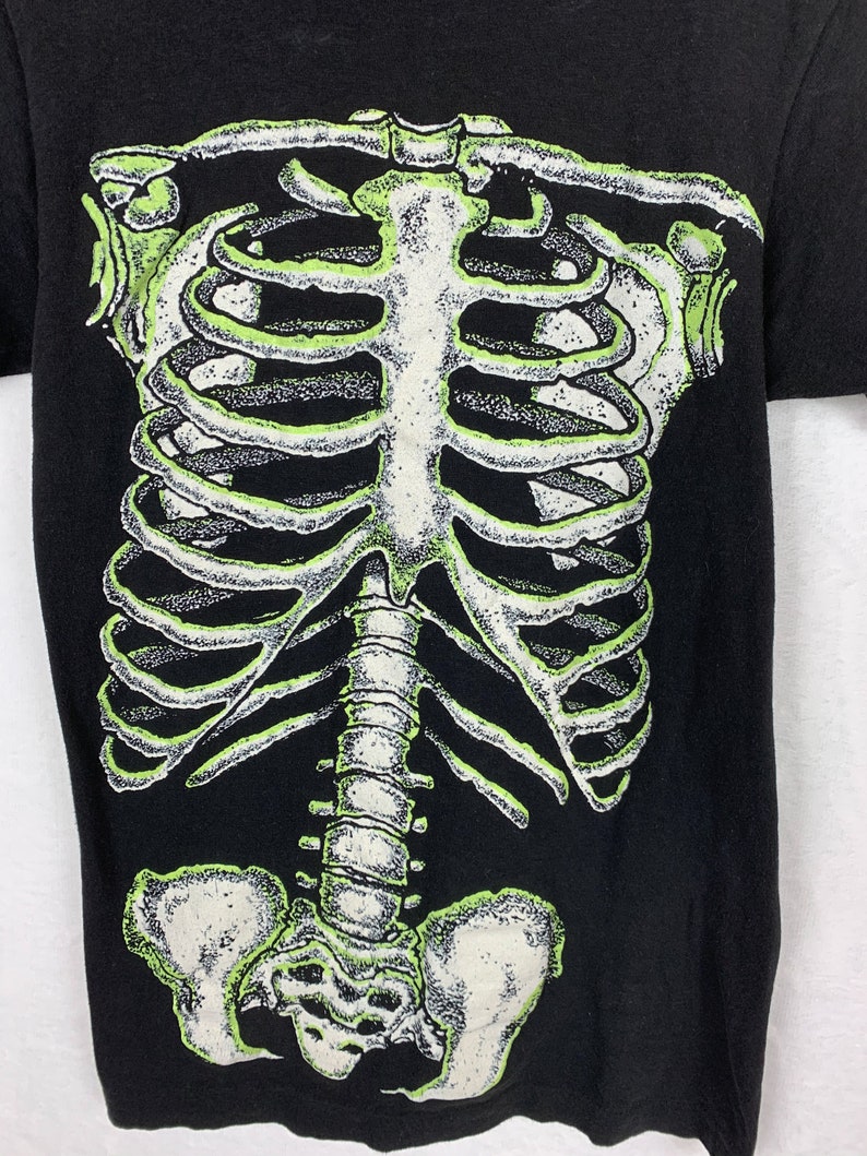 Op de afbeelding: Zwart T-shirt met een groene en witte skeletprint op de voorkant.