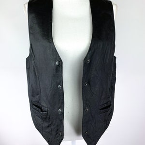 May include: A black leather vest with a V-neck and multiple button fastenings. The vest has two pockets on the front.