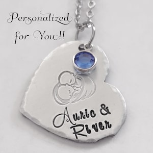 May include: A silver heart-shaped pendant necklace with a blue crystal charm. The pendant is engraved with the names "Auric & River" and a design of two babies sleeping.