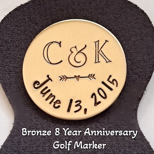May include: Bronze golf marker with a leather holder. The marker is engraved with the initials "C&K" and the date "June 13, 2015". The text "Bronze 8 Year Anniversary Golf Marker" is printed below the marker.