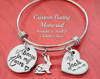 Könnte beinhalten: Silbernes, ausziehbares Armband mit drei Anhängern: ein runder Anhänger mit dem Text "Always in my heart", ein Hasenanhänger und ein Herzanhänger mit dem Text "Jack".  Individuelle Hasen-Gedenk-Armband. Erhältlich in Erwachsenen- und Kindergrößen.