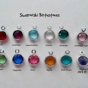 May include: A collection of 12 Swarovski birthstone charms, each with a different color and name. The charms are arranged in two rows of six. The charms are out of stock.