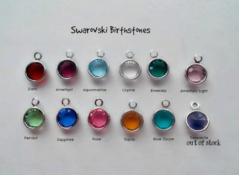 May include: A collection of 12 Swarovski birthstone charms, each with a different color and name. The charms are arranged in two rows of six. The charms are out of stock.