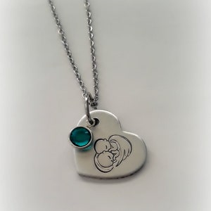 May include: A silver heart-shaped pendant necklace with a small teal gemstone and an engraved image of two babies.