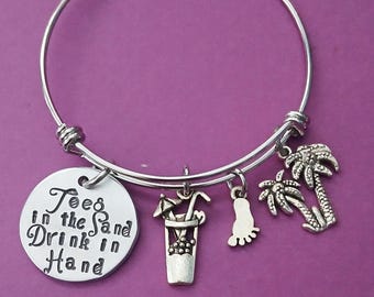 May include: Silver charm bracelet with a charm that says "Toes in the Sand Drink in Hand" and other charms including a palm tree, a footprint, and a cocktail glass.