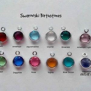 May include: A chart of Swarovski birthstones, showing a variety of colors and styles. The birthstones are arranged in two rows, with the names of each stone listed below. The chart includes the following birthstones: Siam, Amethyst, Aquamarine, Crystal, Emerald, Amethyst Light, Peridot, Sapphire, Rose, Topaz, Blue Zircon, and Tanzanite.