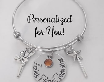 Puede incluir: Un brazalete de plata con un dije que dice "Izzies Fairy Godmother". El brazalete también tiene un dije de hada, un dije de estrella y una pequeña gema naranja.