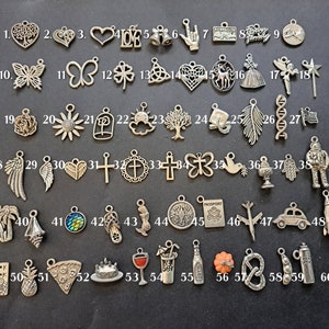 May include: Sixty silver charm pendants with various designs, including hearts, butterflies, flowers, crosses, and a passport. The charms are numbered 1 through 60.