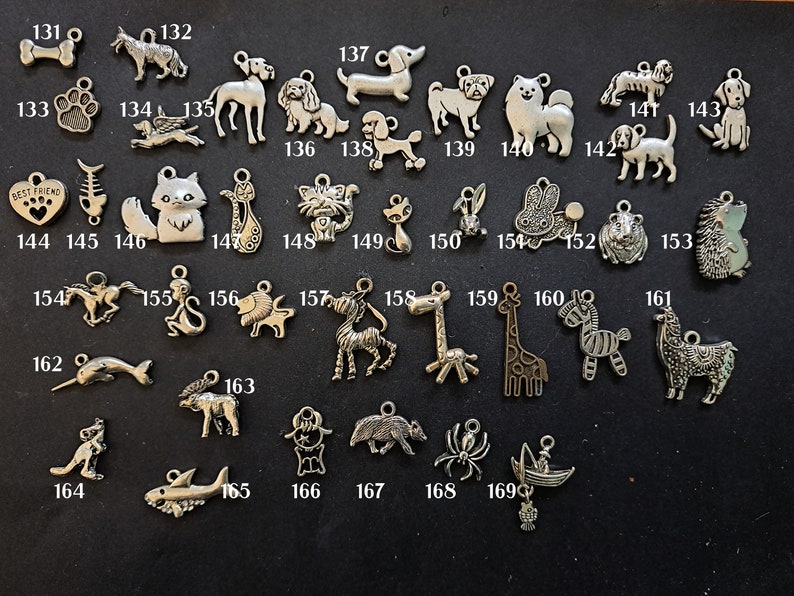 May include: A collection of silver charm pendants featuring various animal designs, including a dog, cat, horse, giraffe, zebra, and more. The charms are numbered 131 to 169.
