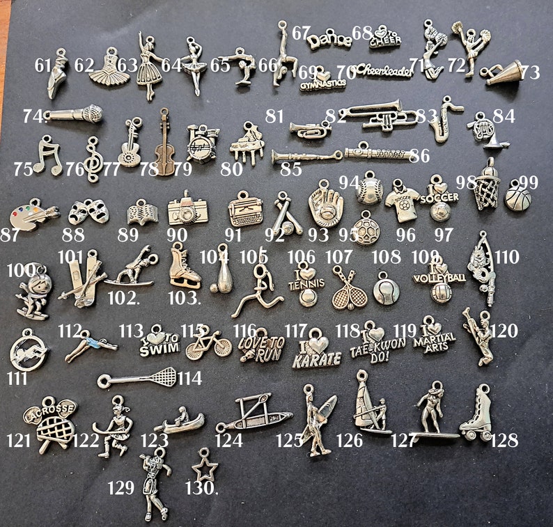 May include: A collection of 130 silver charms featuring various sports, activities, and hobbies. The charms are arranged in rows on a white background. Some of the charms include a basketball, a soccer ball, a baseball, a tennis racket, a volleyball, a skateboard, a bicycle, a running shoe, a karate belt, a microphone, a musical note, a violin, a piano, a paintbrush, a pair of glasses, a camera, a typewriter, a baseball glove, a soccer jersey, a basketball hoop, a ski, a snowboard, a baseball bat, a tennis ball, a volleyball, a cross, a lacrosse stick, a canoe, a surfboard, a skateboard, a roller skate, and a star.