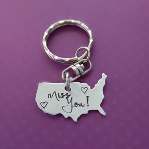 May include: Silver keychain shaped like the United States with the words "Miss You!" and three small hearts engraved on it.