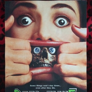 Puede incluir: Un póster de película de terror para la película "Dead-Alive". El póster presenta un primer plano de la cara de una mujer con la boca abierta, revelando la cabeza de un zombi con ojos azules brillantes. El lema dice "Algunas cosas no se quedan abajo... incluso después de que mueren."