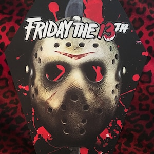 May include: A black and red coffin-shaped sticker with a white "FRIDAY THE 13TH" logo and a white hockey mask with red blood splatters.