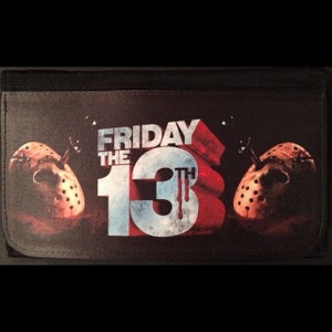 May include: Black wallet featuring the text "FRIDAY THE 13TH" in white, red, and blue. The design includes two hockey masks and a blood-dripping "13".