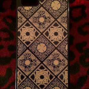 May include: A black iPhone case with a white and brown geometric pattern. The pattern is a repeating design of interlocking squares and circles.