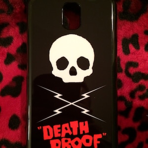 May include: Black phone case with a white skull and crossbones graphic and the text "DEATH PROOF" in red.