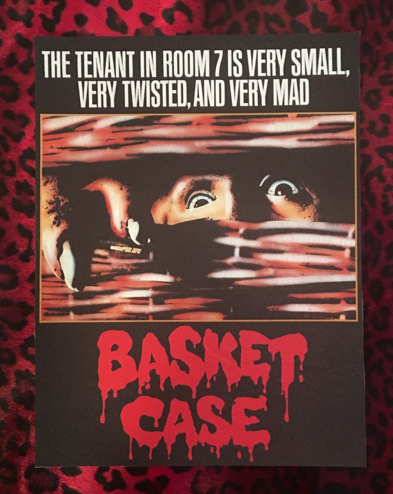 May include: A vintage movie poster for the horror film "Basket Case". The poster features a close-up of a person's face peering through a wicker basket, with the text "THE TENANT IN ROOM 7 IS VERY SMALL, VERY TWISTED, AND VERY MAD" at the top and "BASKET CASE" in red dripping letters at the bottom.