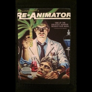 May include: A vintage movie poster for the horror film "Re-Animator" by H.P. Lovecraft. The poster features a scientist holding a test tube and a severed head in a lab setting. The text "One of the greatest horror movies ever made" is featured on the poster.