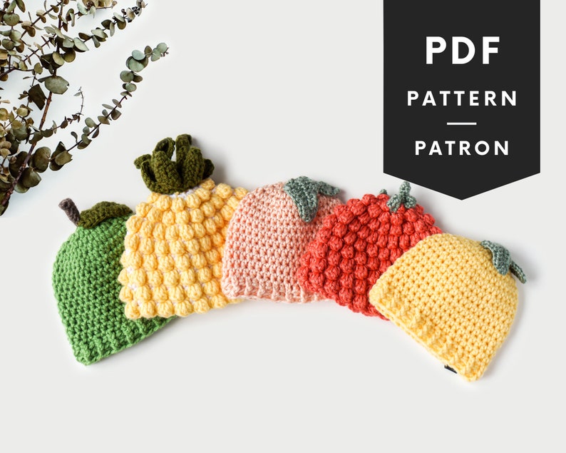May include: Five crocheted hats in the shape of different fruits: a lime, pineapple, peach, strawberry, and lemon. The hats are arranged in a semi-circle on a white surface.  PDF PATTERN PATRON