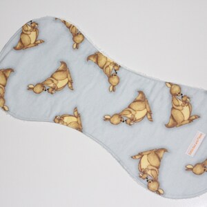 May include: A light blue baby burp cloth with a kangaroo pattern. The cloth has a white border and a small tag that says "Little Bear Paws".