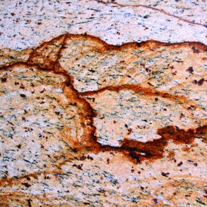Puede incluir: Primer plano de una encimera de granito de color marr&oacute;n claro, beige y naranja con un patr&oacute;n de vetas marrones oscuras en espiral.